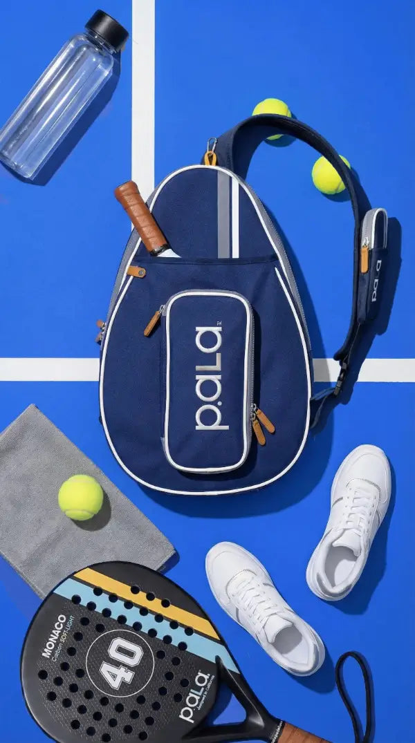 Pala paddle sports bag with tennis balls, shoes, and paddle on a blue background
