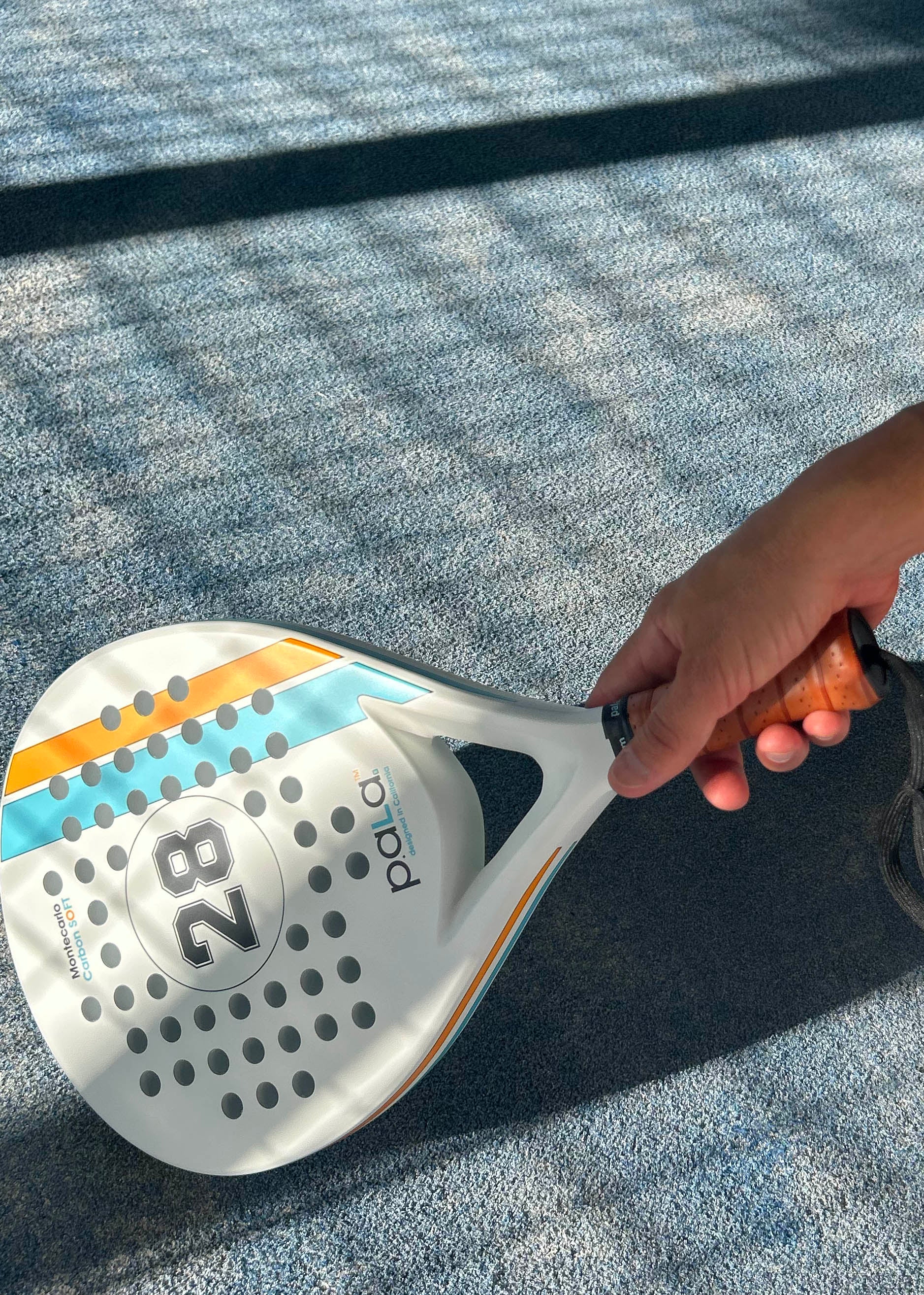 P.ALA PADEL RACKET IN A BLUE PADEL COURT