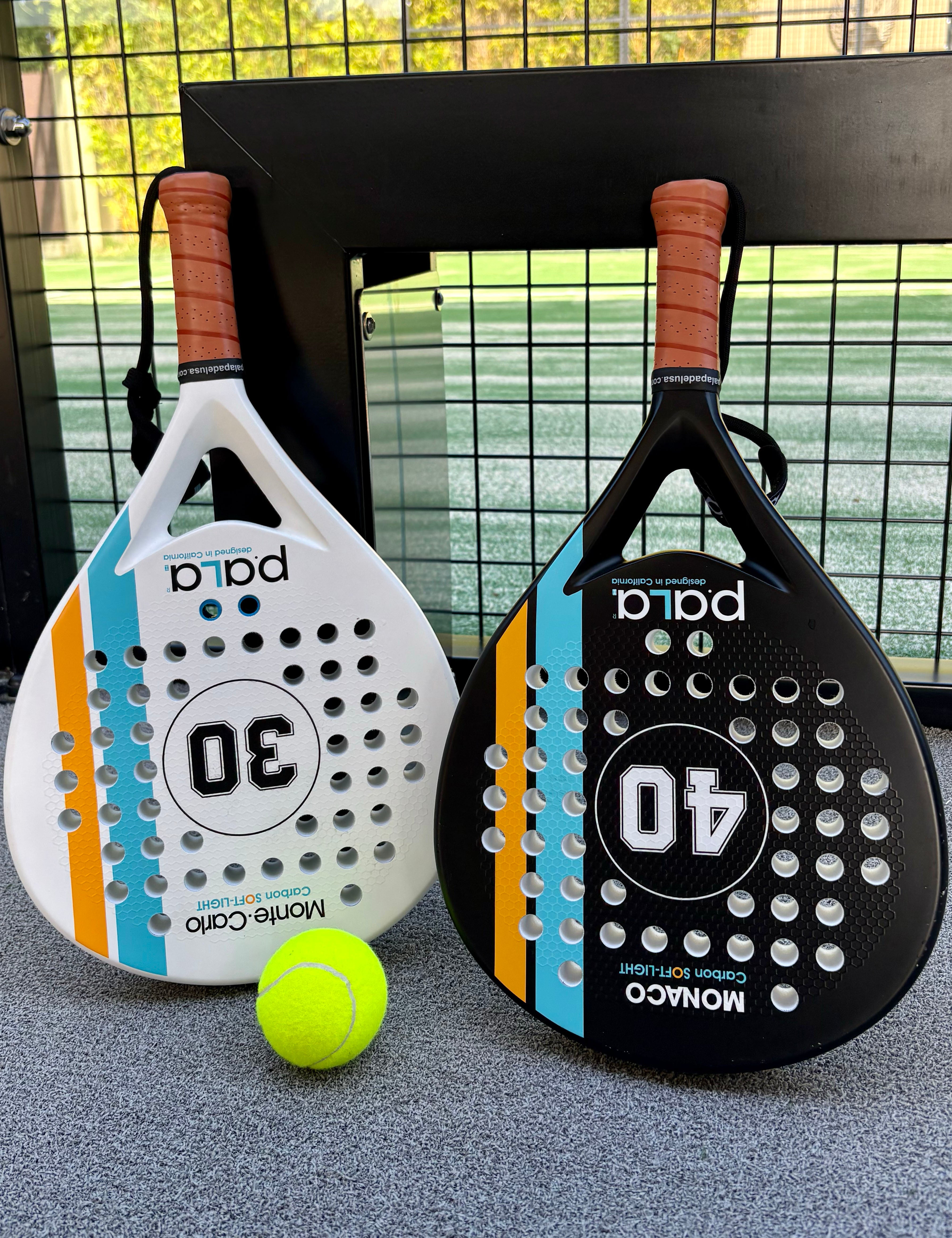 Two paddle tennis rackets with a ball on a court background